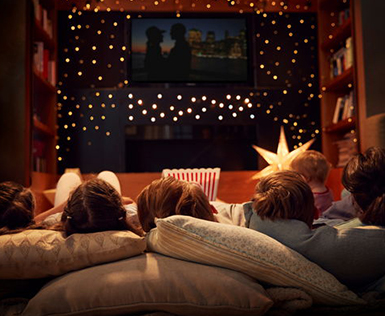 whole family on a couch watching tv with christmas lights