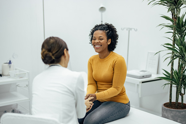 Excited woman happy to hear good news from a doctor. Doctor and patient holding hands and smiling at private practice.